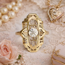 Load image into Gallery viewer, Gold ring with diamond on a decorative surface with pearls and a rose.