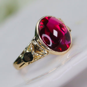 Smooth top oval synthetic ruby ring in yellow gold